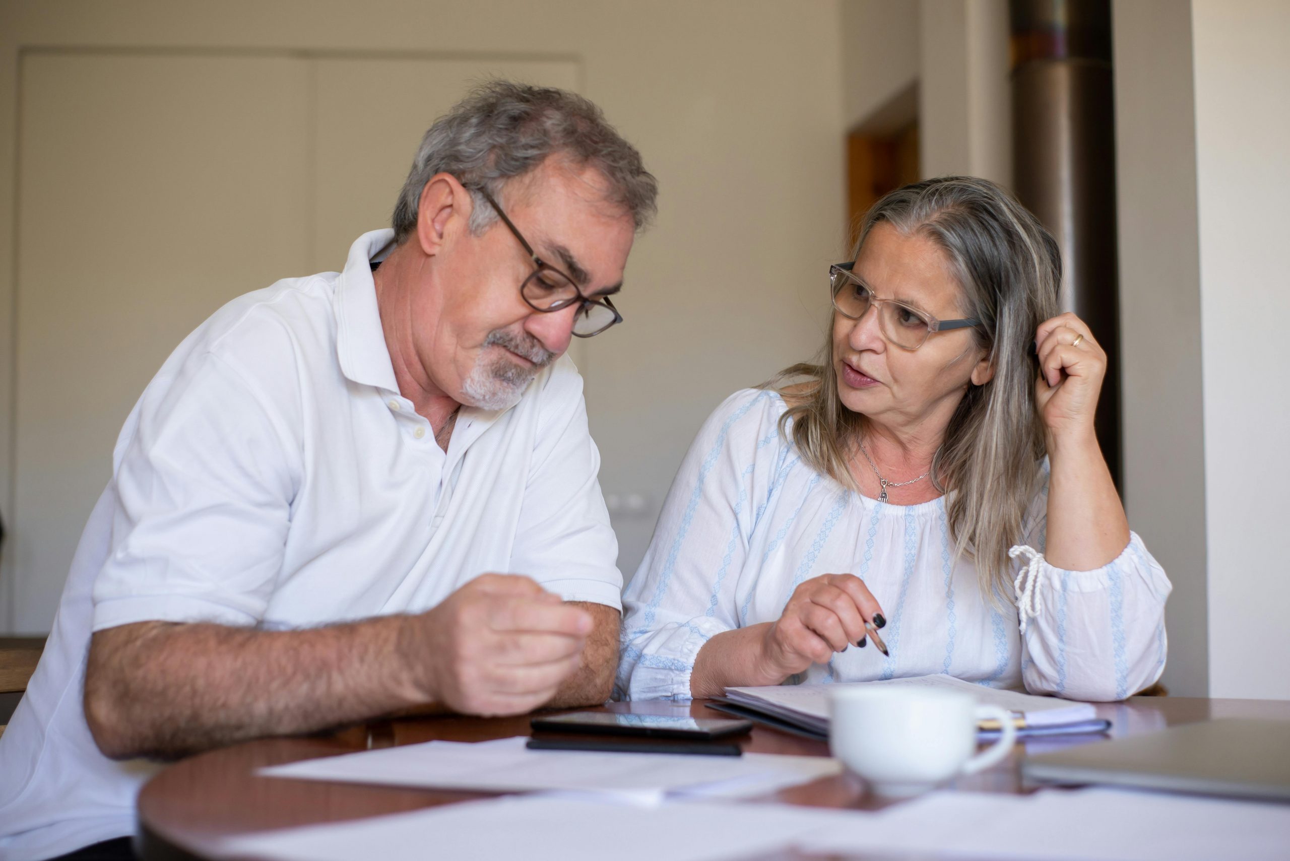 older couple sitting at a table discussing something while looking at documents