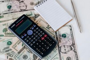 a calculator and a notepad over dollar bills